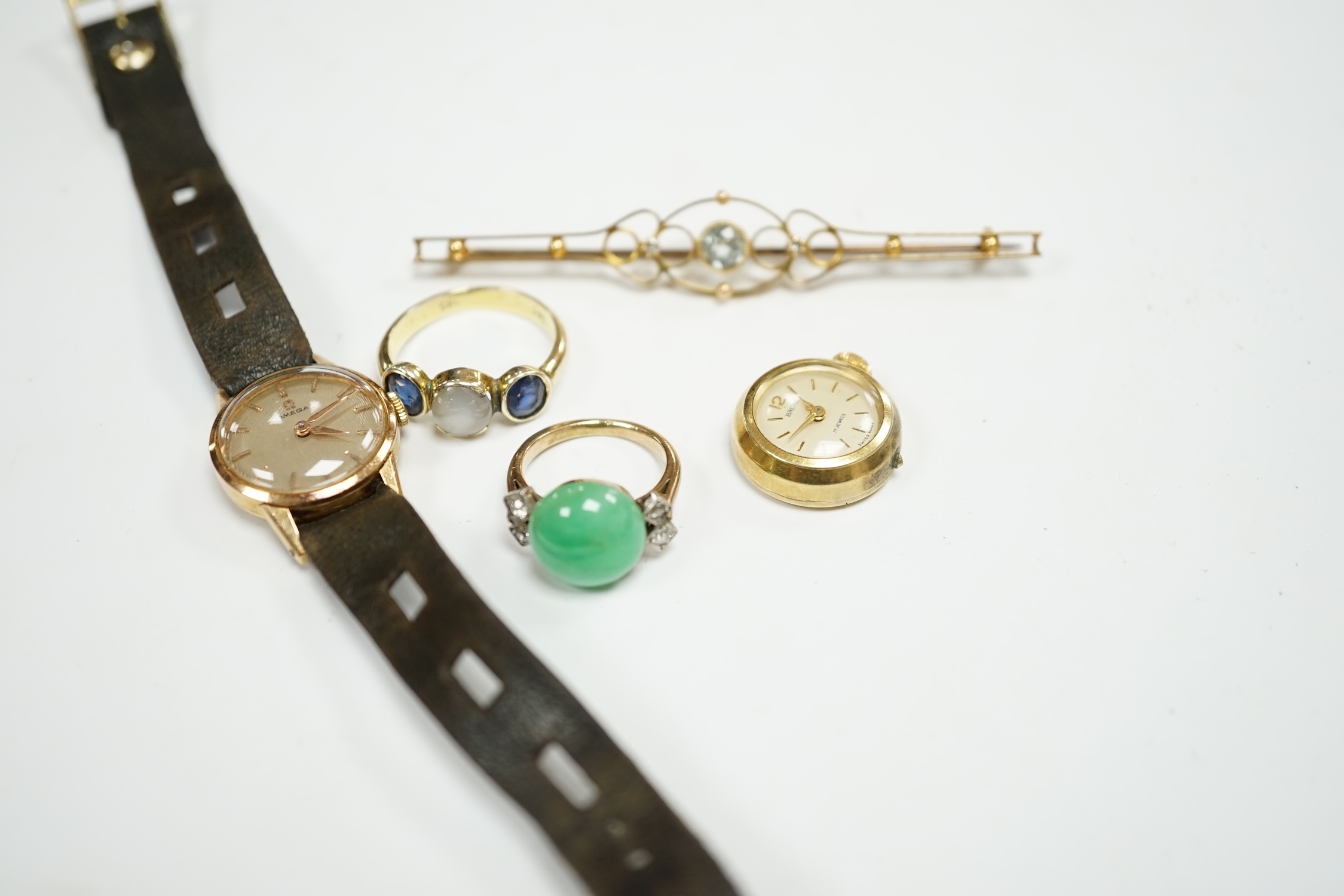 An Edwardian 15ct, aquamarine and diamond set three stone bar brooch, 74mm, a lady's yellow metal Omega manual wind wrist watch, a lady's rolled gold wrist watch a 14k and three stone sapphire ring the central stone a wh